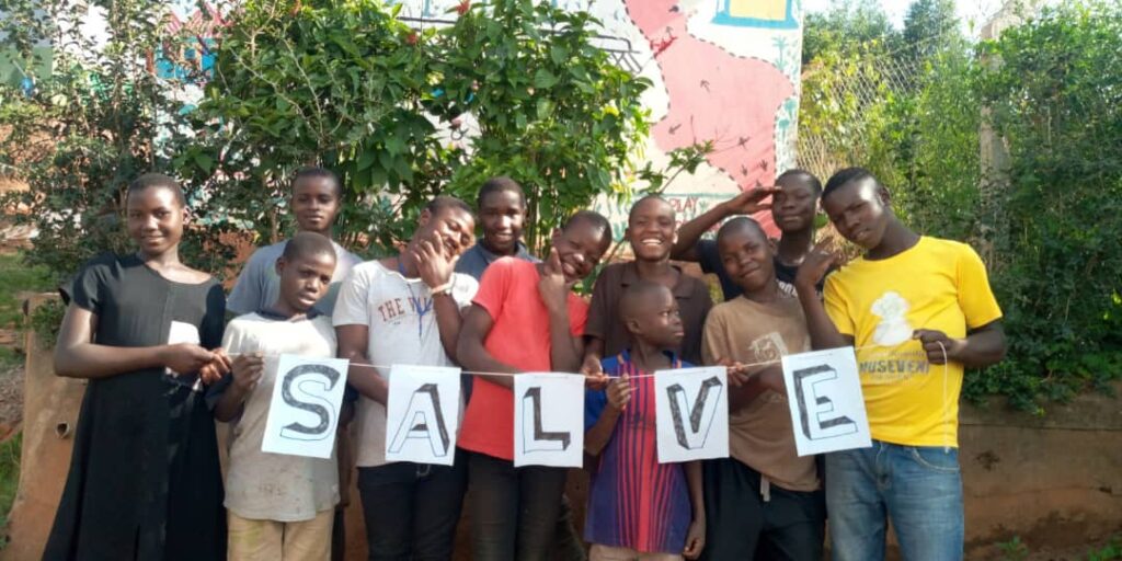 A group of children. The ones at the front hold up a S.A.L.V.E banner