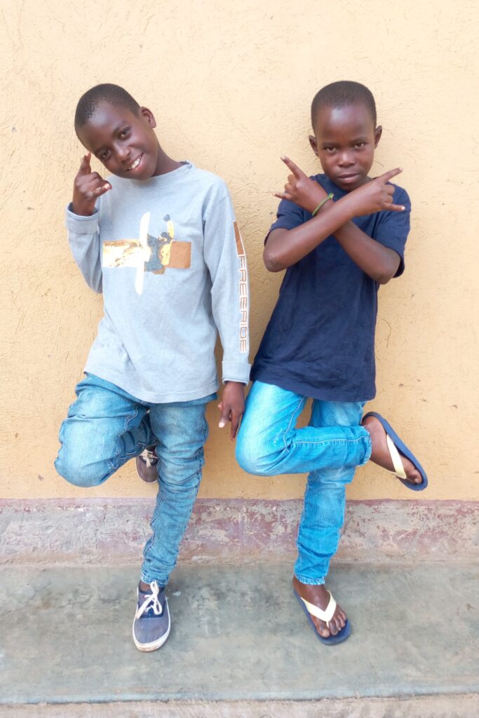 Two boys posing learning against a wall