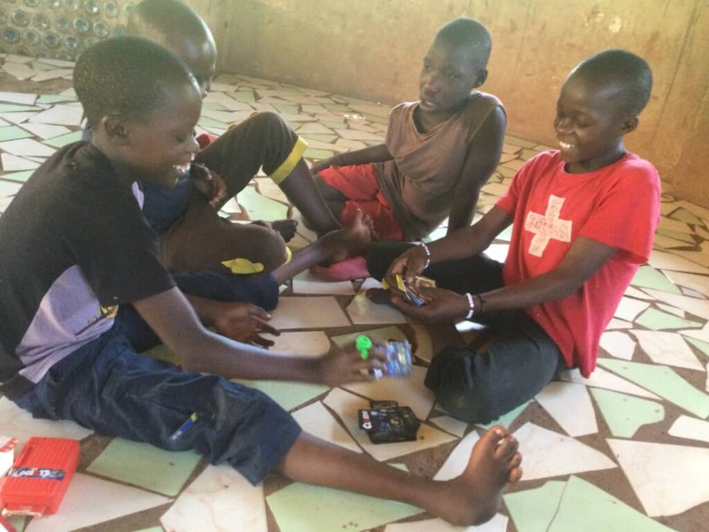 children smiling together and playing a game, sat on the floor