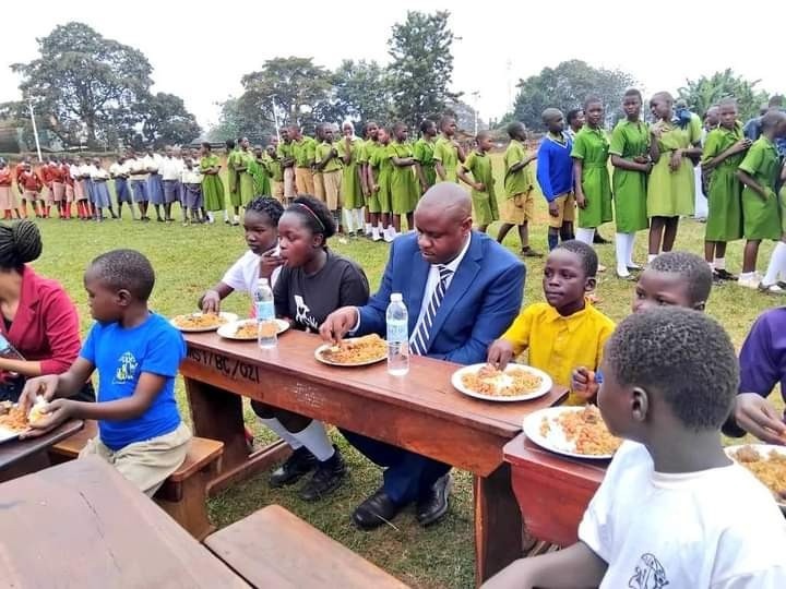 Two adults and some young people sitting down and eating a table together