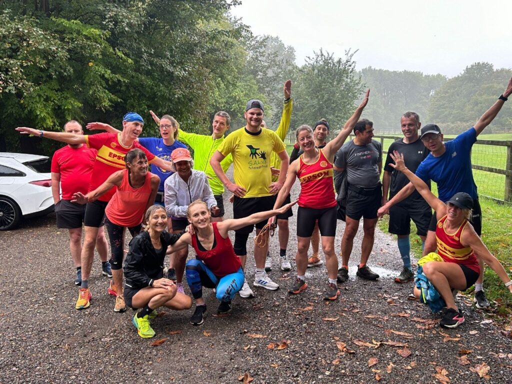 Lucas Mee is standing with Helen Maguire and other members of a running club. They are posing for the camera wearing their running clothes.